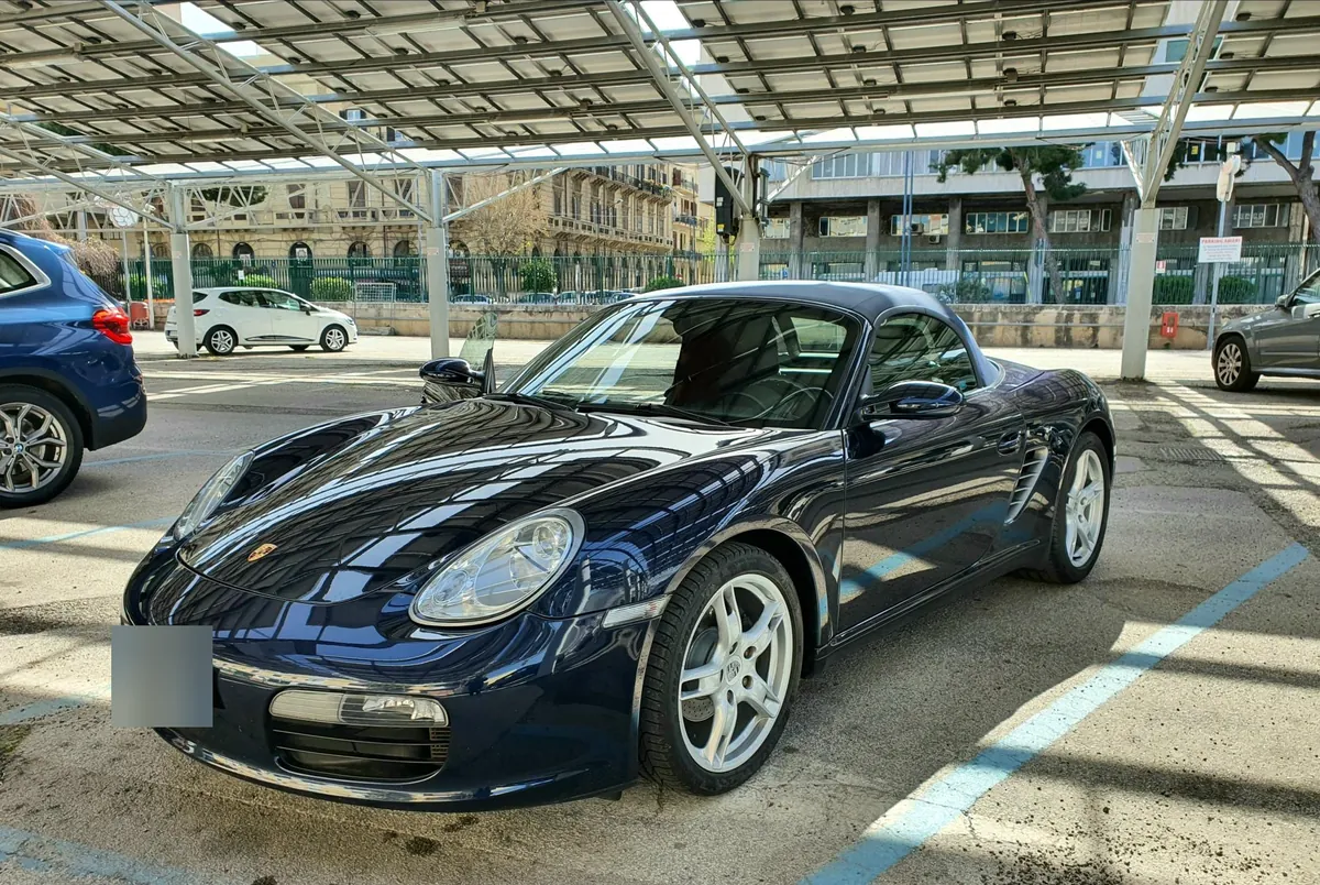La Boxster blu con la capote chiusa, vista di tre quarti anteriore sotto una pensilina di pannelli solari