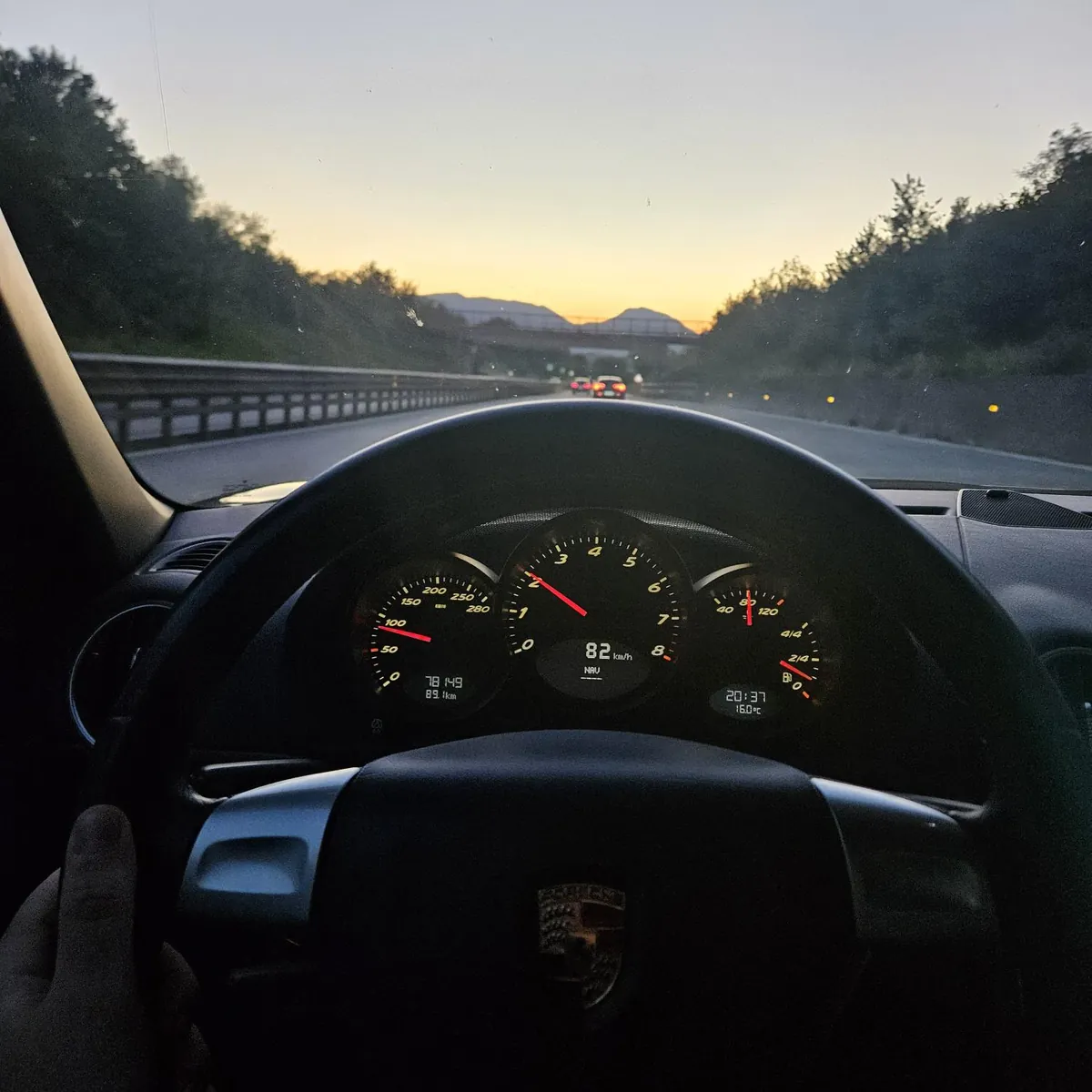 Il cruscotto a tre strumenti visto dal posto di guida, in autostrada al tramonto