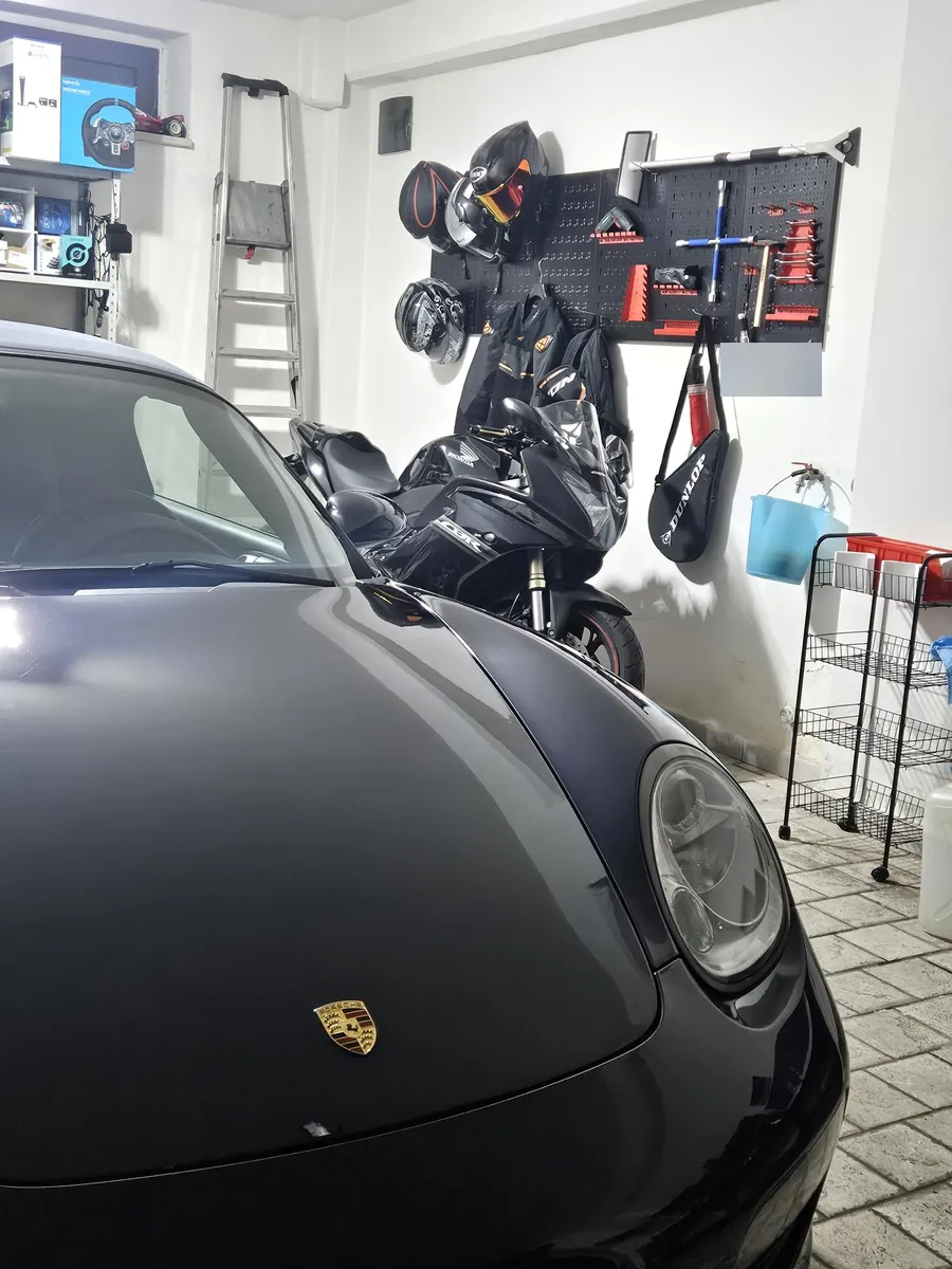 Il cofano della Boxster in garage, con la moto e la parete degli attrezzi sullo sfondo