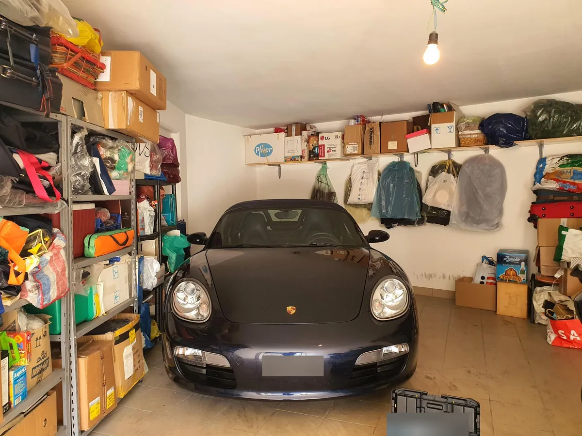La Boxster vista di fronte in un garage pieno di scaffali, scatoloni e borse