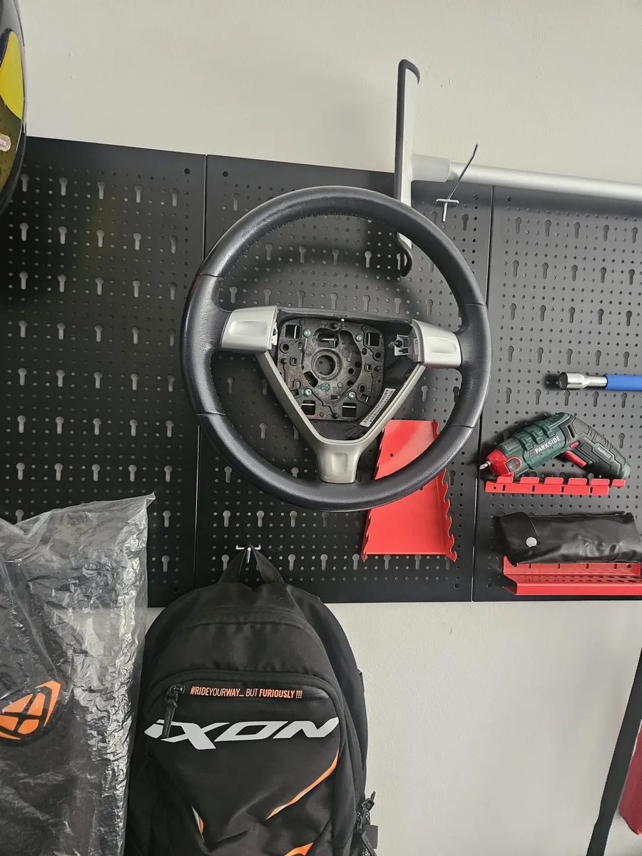 Un volante Porsche senza airbag appeso alla parete degli attrezzi