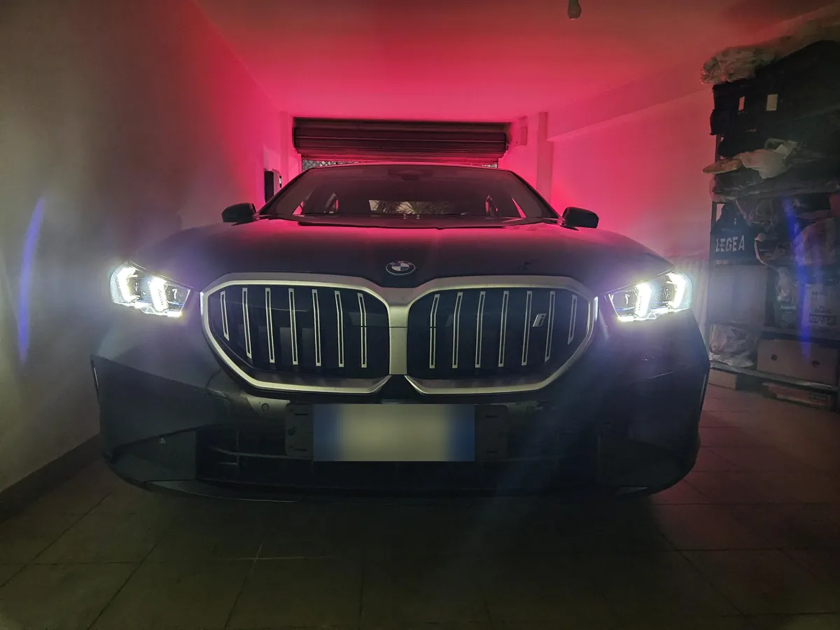 La i5 nera vista di fronte in un garage illuminato di rosso, con i fari accesi