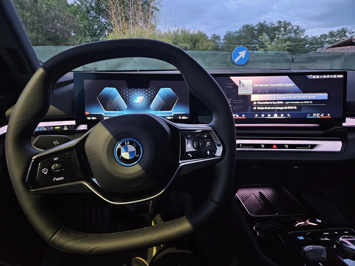 Il posto di guida della i5: volante, cruscotto digitale e schermo curvo acceso