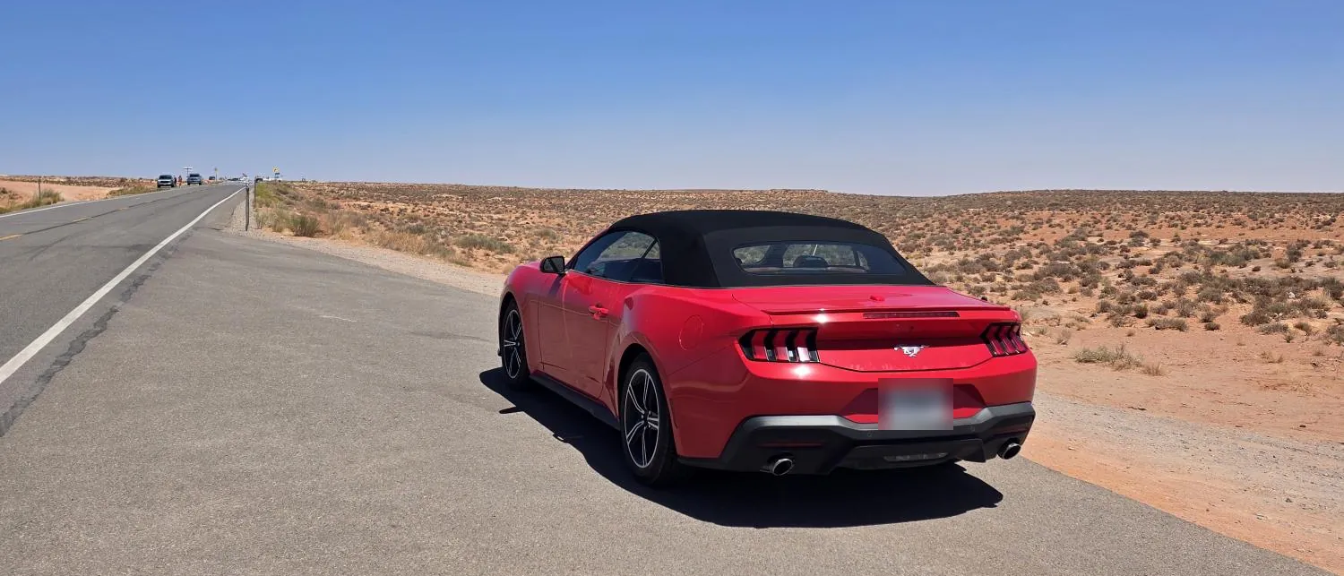 La Mustang rossa con la capote chiusa, ferma sul bordo di una strada nel deserto