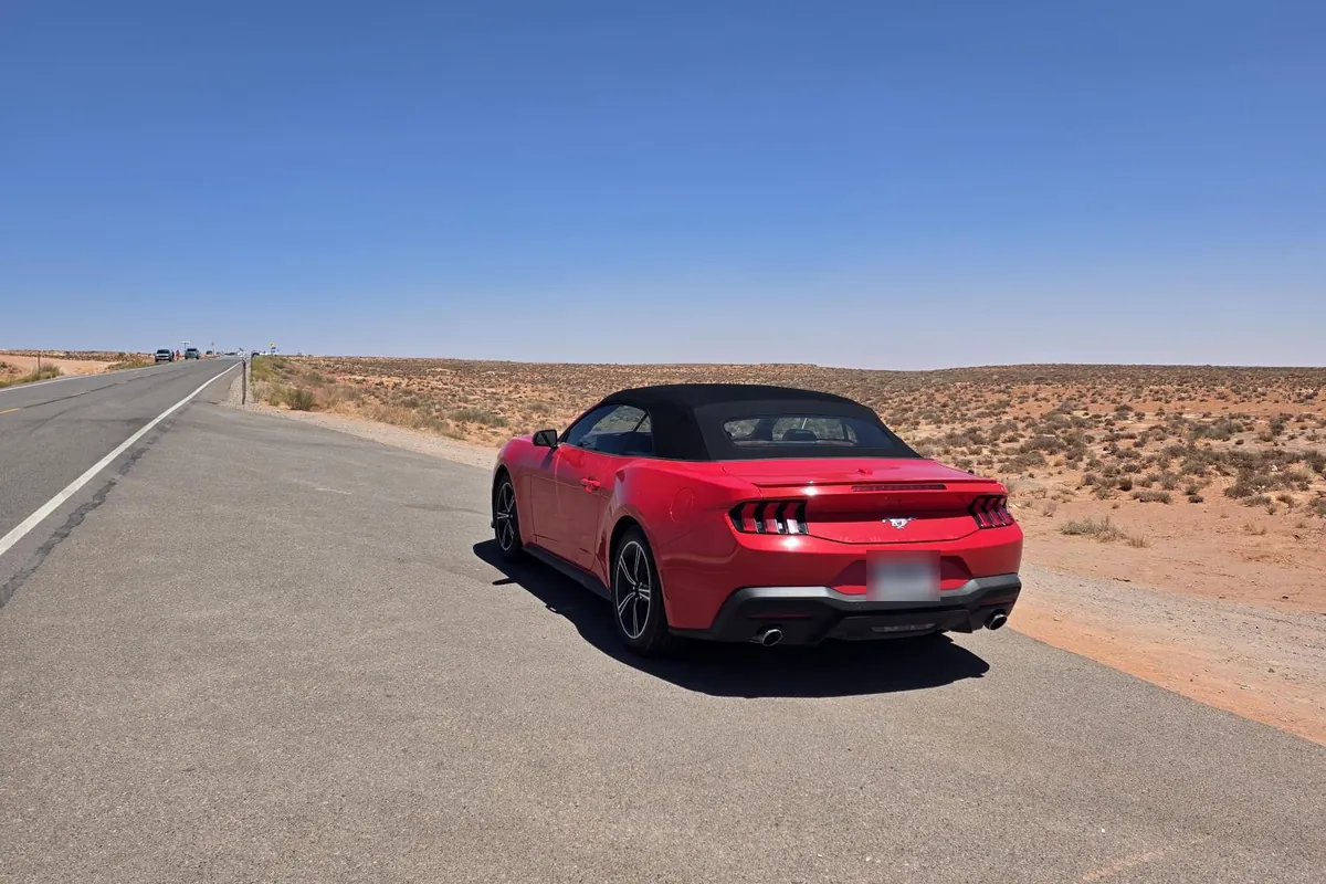 La Mustang rossa con la capote chiusa, ferma sul bordo di una strada nel deserto