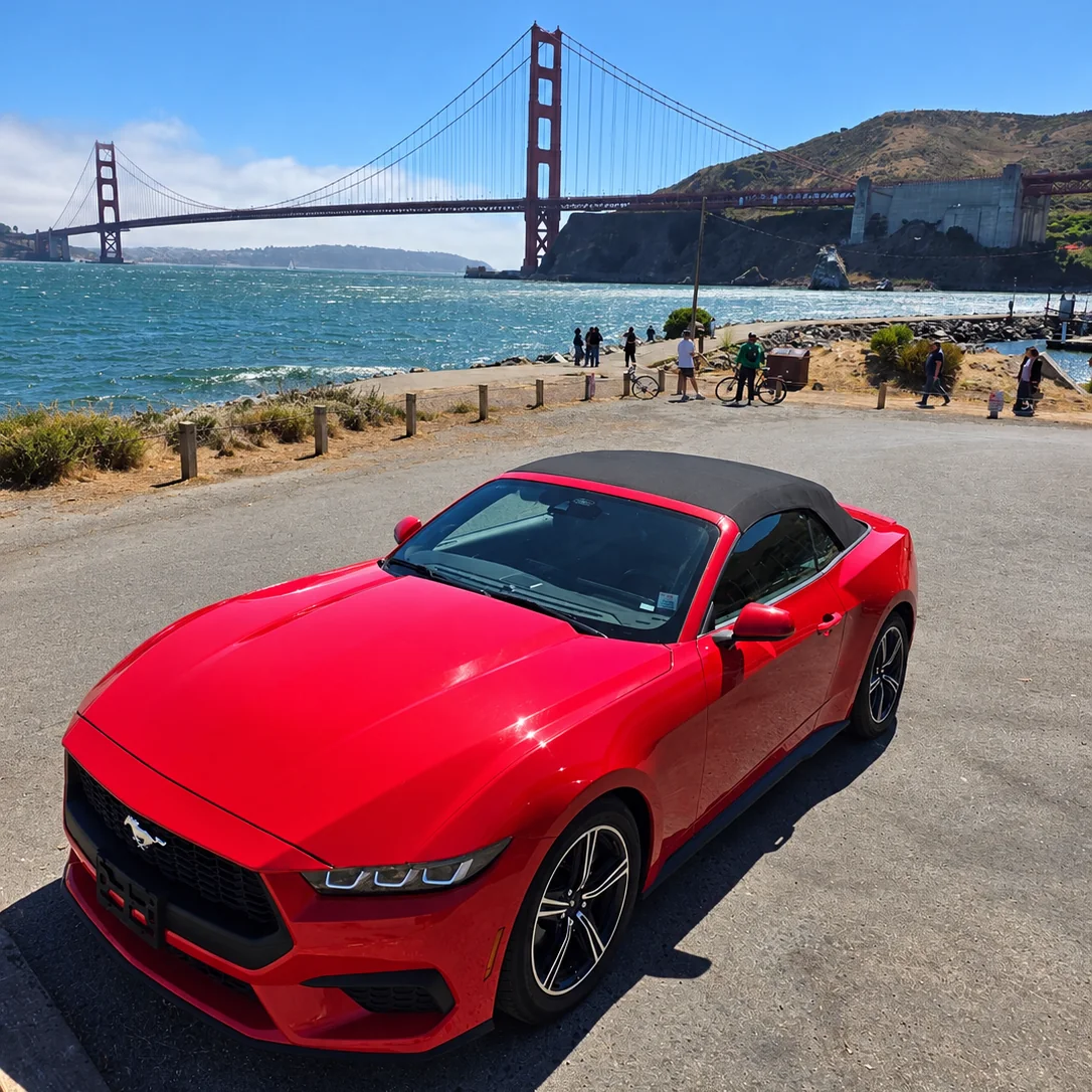 La Mustang rossa con la capote chiusa in un piazzale sulla baia di San Francisco, con il Golden Gate sullo sfondo