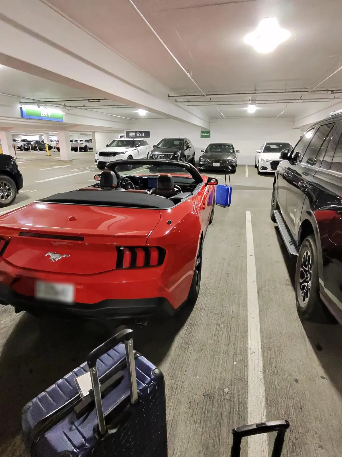 La Mustang aperta in un parcheggio coperto, con una valigia accanto